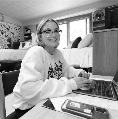 Smiling studen working on laptop in dorm room